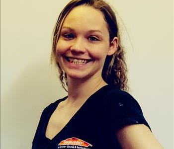 young woman with long blonde hair in a ponytail smiling at the camera